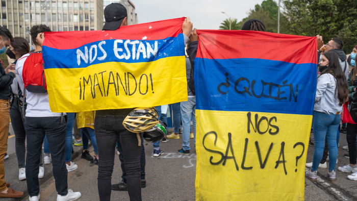 two people at a protest are holding Colombian flags