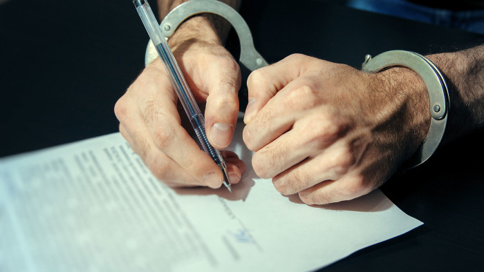 Person in handcuffs signing a statement