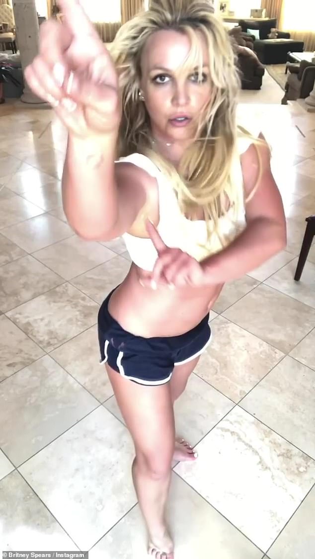 Britney Spears joyfully dances around her living room in a white bralette top after revealing she is writing a book about a murdered girl’s ghost
