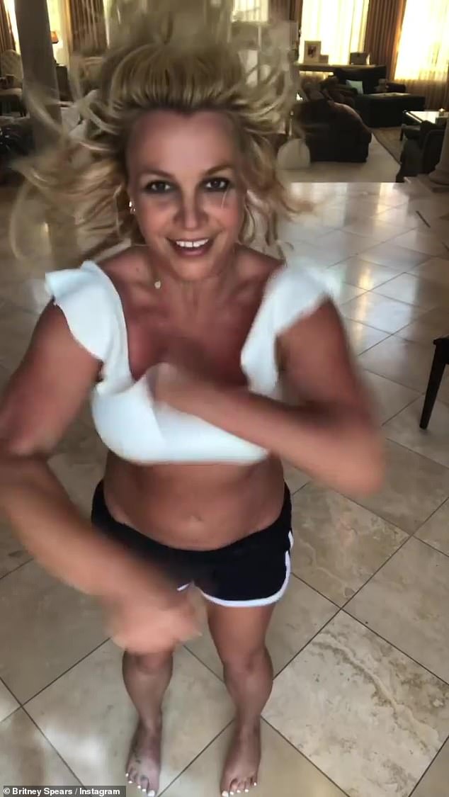 Britney Spears joyfully dances around her living room in a white bralette top after revealing she is writing a book about a murdered girl’s ghost