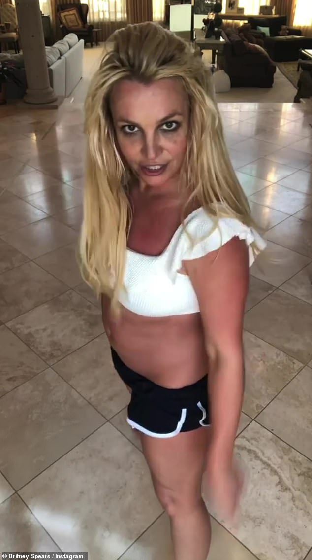 Britney Spears joyfully dances around her living room in a white bralette top after revealing she is writing a book about a murdered girl’s ghost