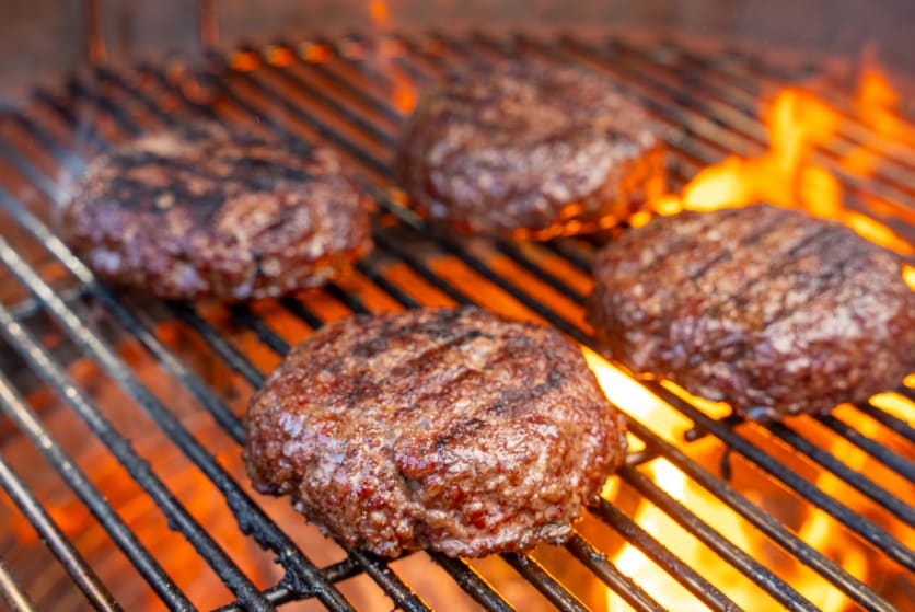 Smoked hamburgers searing over charcoal