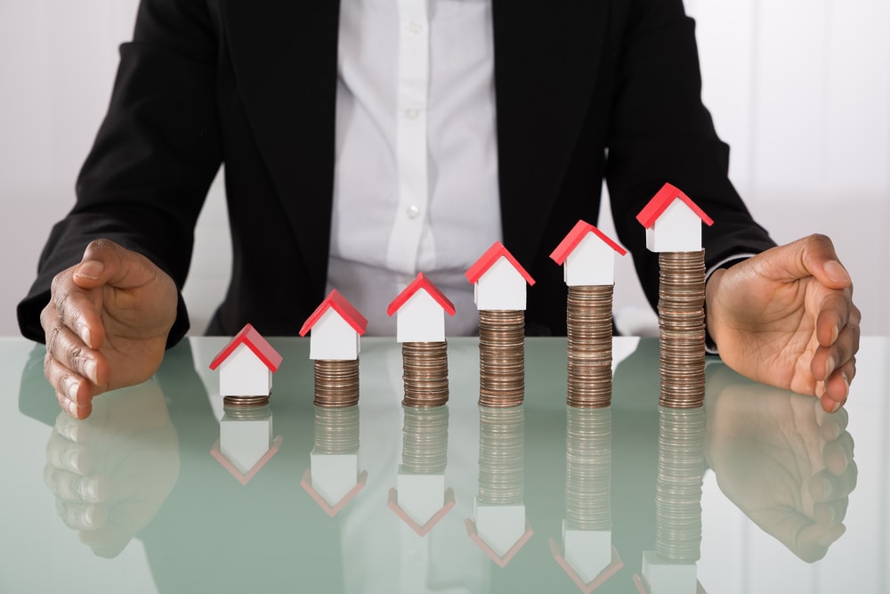 Businesswoman Protecting House Models On Stacked Coins franchise investment