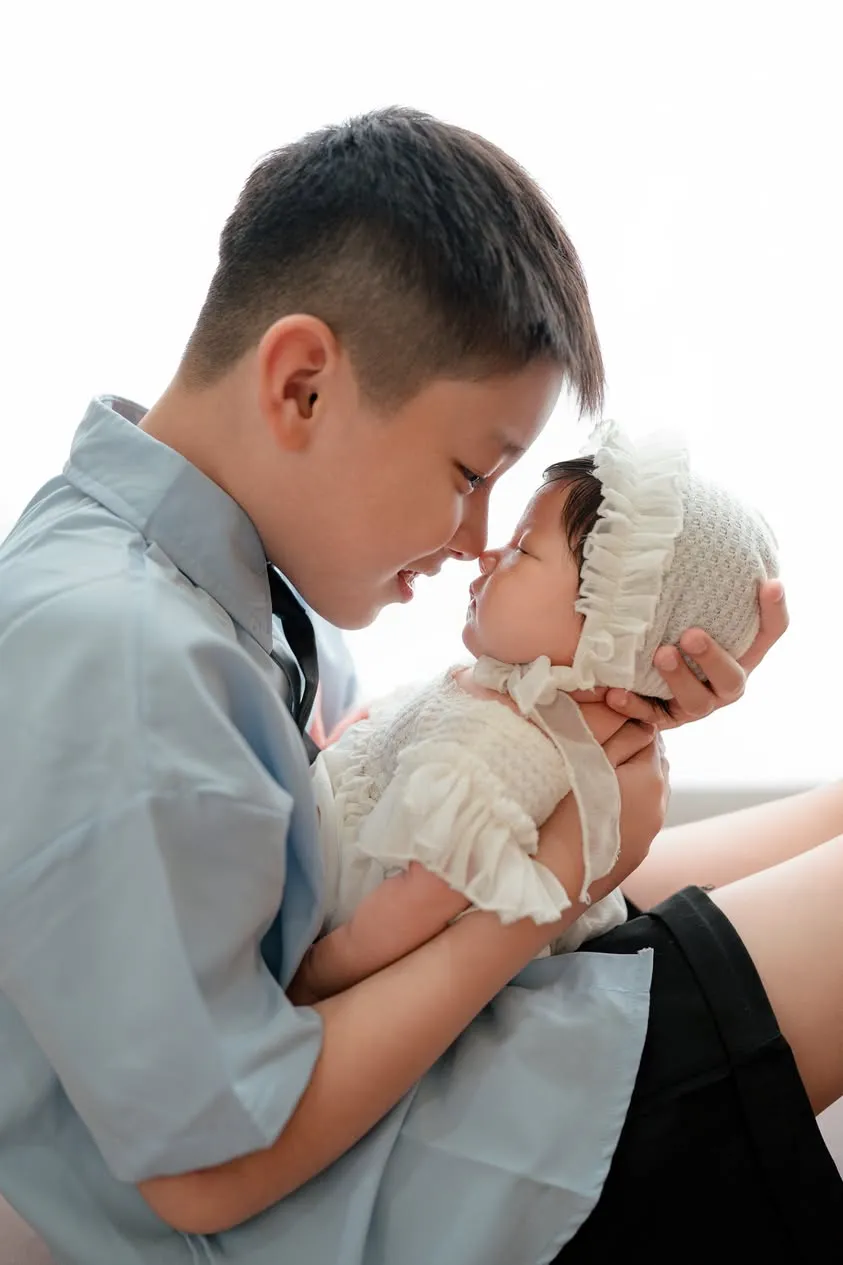 Bé một tháng tuổi được anh trai bế ôm ấp trong buổi chụp ảnh đầy tháng cùng gia đình