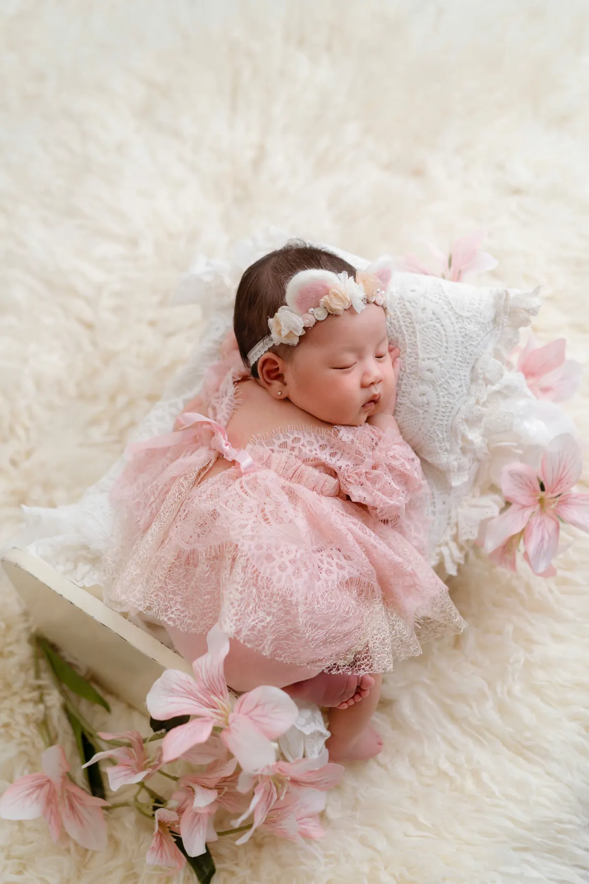 Bé sơ sinh nằm chơi trong váy hồng — lịch tiêm chủng cho bé bắt đầu từ những tuần đầu đời