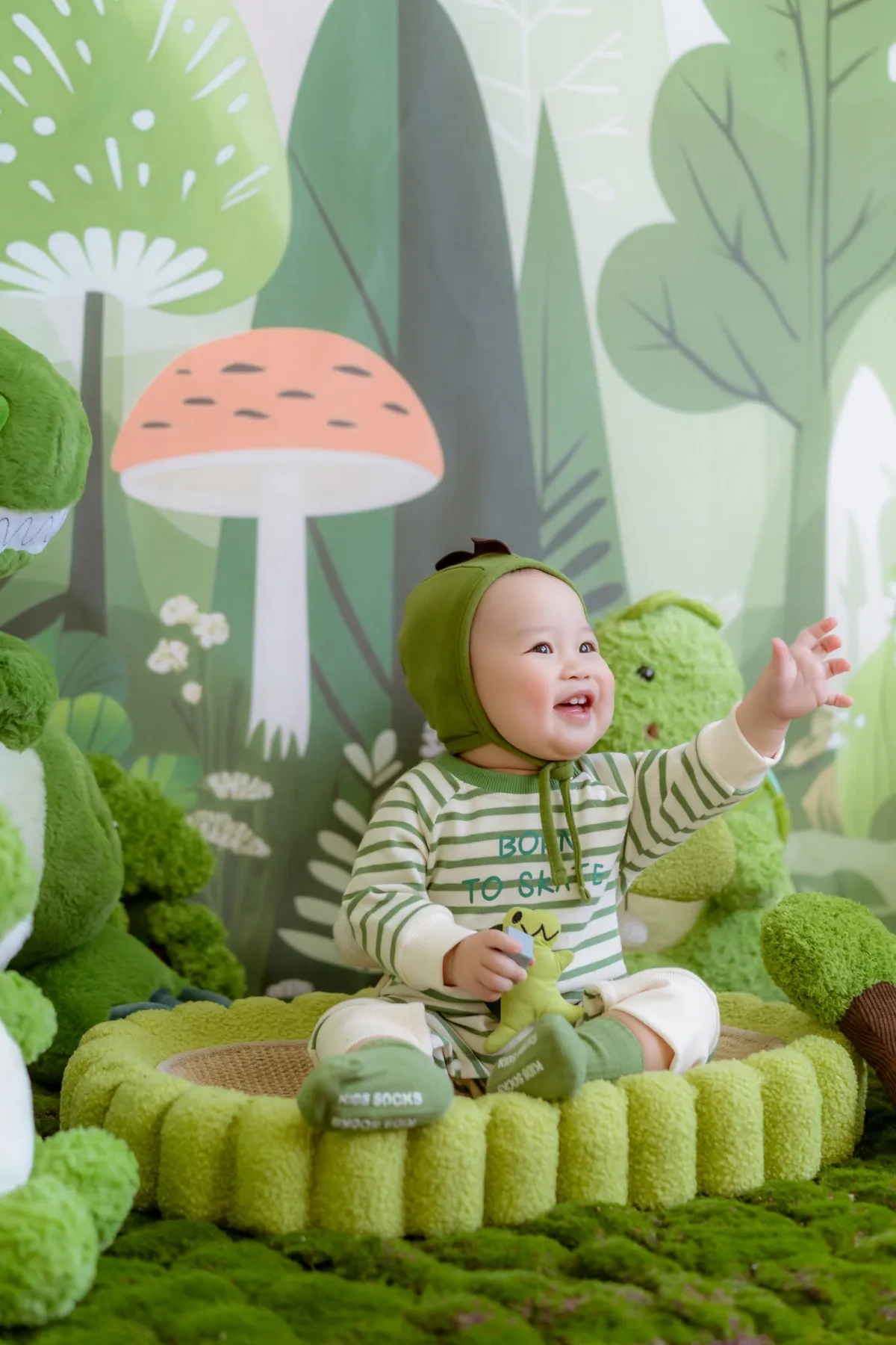 Bé ngồi trong tổ đệm, tay cầm mền — giai đoạn bé 6 tháng bắt đầu tập ăn