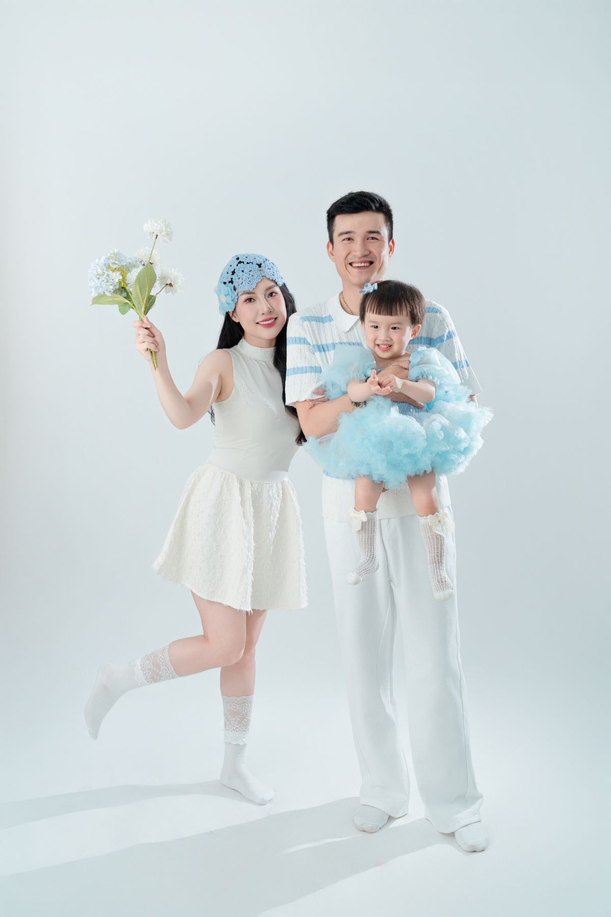 Mẹ cầm bó hoa, ba bế bé gái mặc váy xanh — cuối tuần Đà Lạt cùng bé, ngắm hoa là hoạt động nhẹ nhàng cho cả nhà