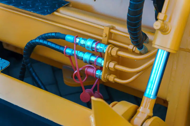 Hydraulic hose quick-connect fittings on yellow equipment