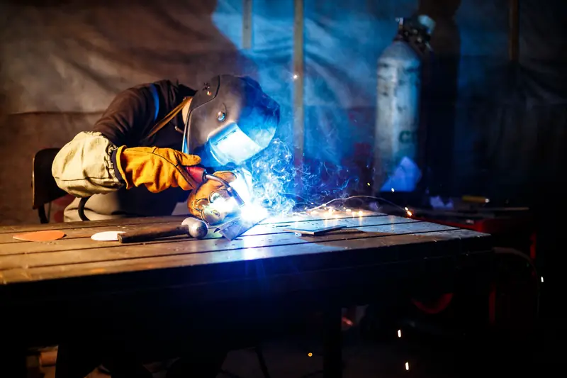 Welder fabricating a metal part with visible sparks