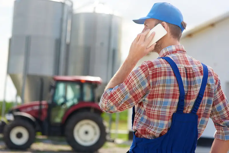 Farmer on the phone at a farm calling in an equipment issue