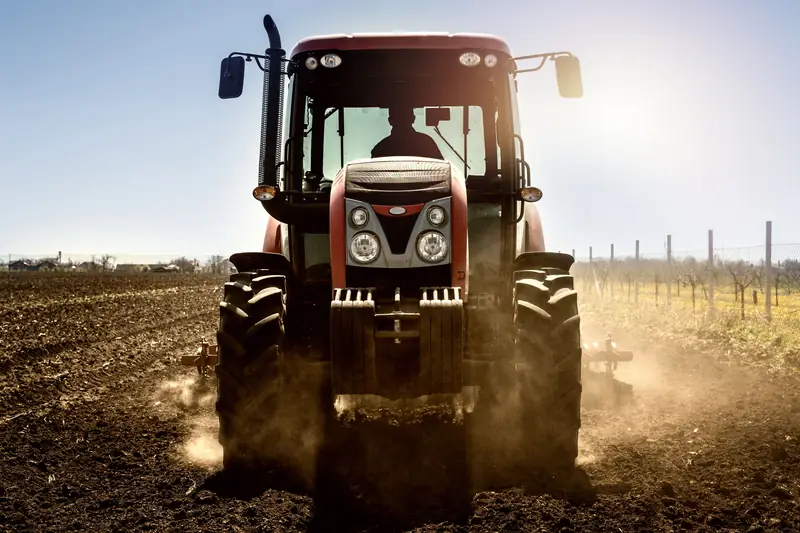 Tractor plowing a dusty field