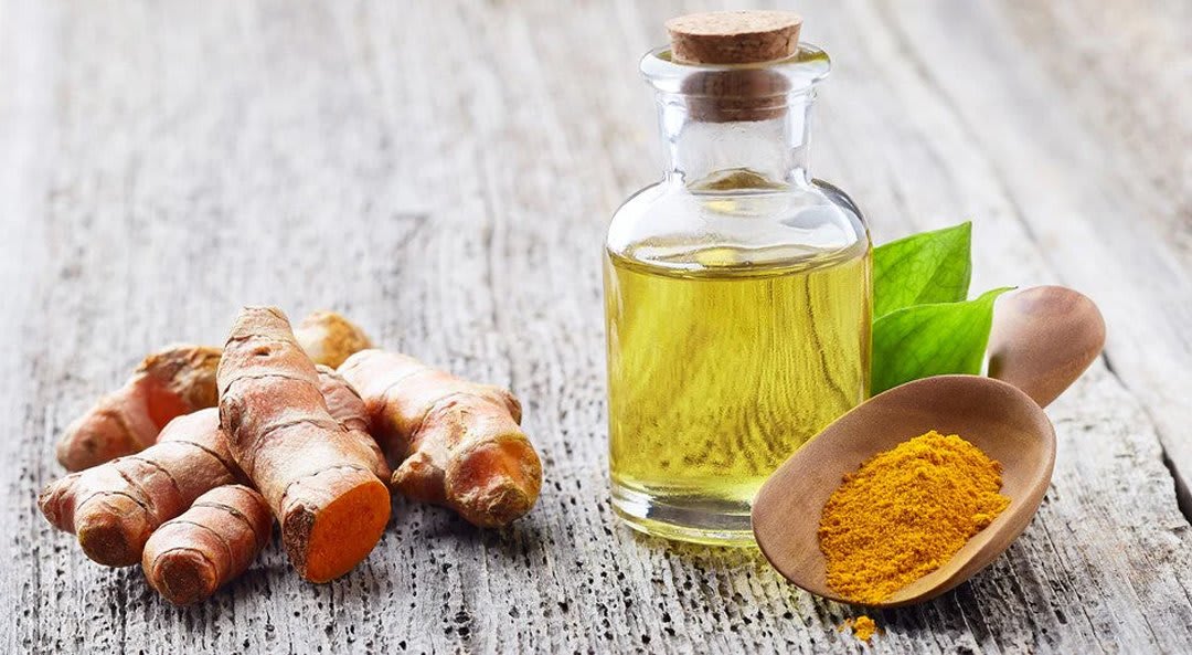 Turmeric oil bottle beside turmeric roots and powder