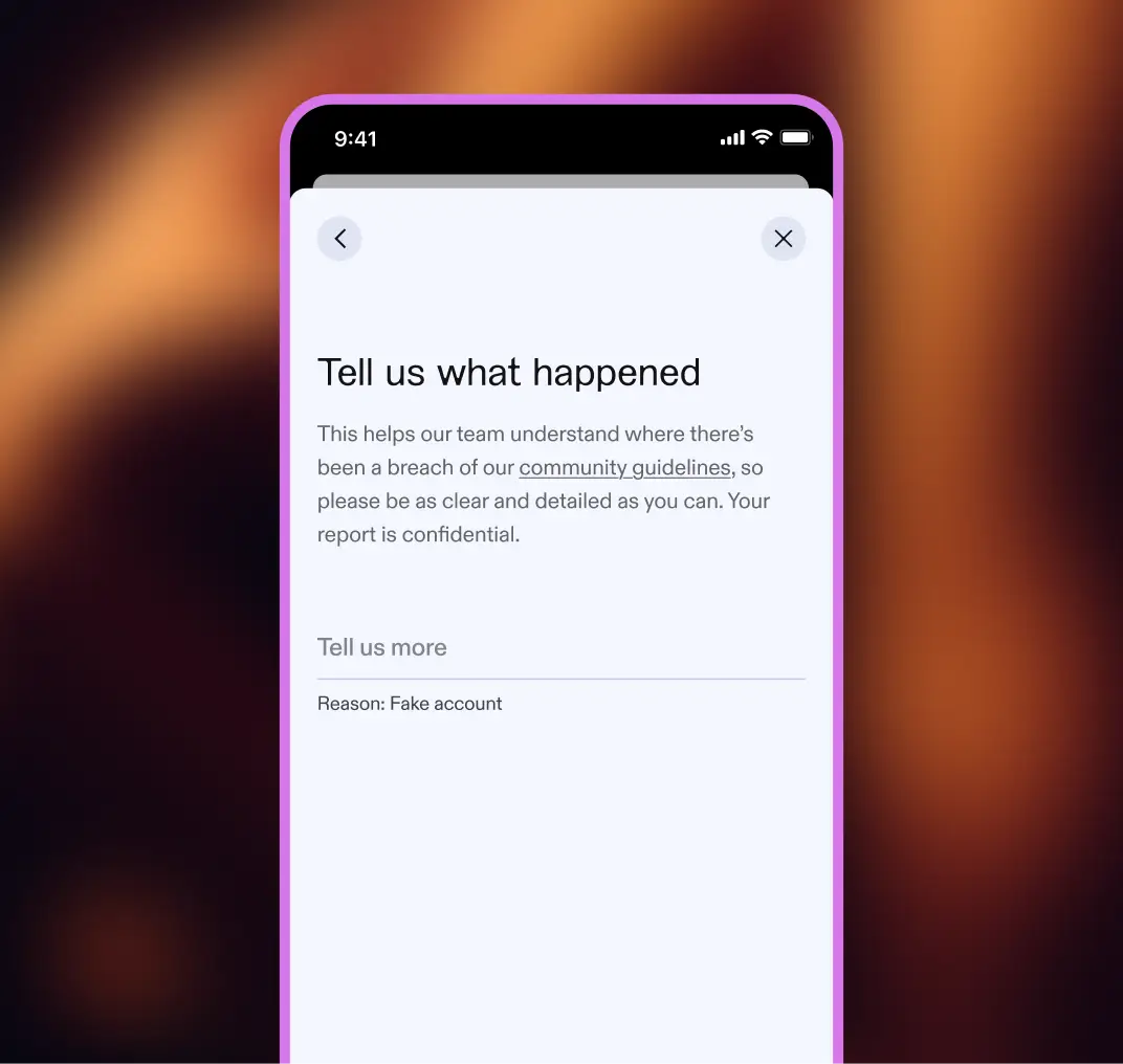 A phone with a purple border showing a "Tell us what happened" reporting screen. Text explains it helps the team understand breaches of community guidelines and notes the report is confidential. Below are a "Tell us more" field and "Reason: Fake account."