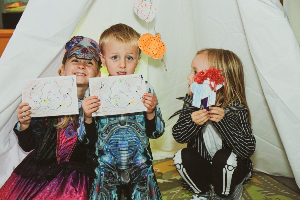 Children in Halloween costumes taking part in a creative activity at ARC Stockton
