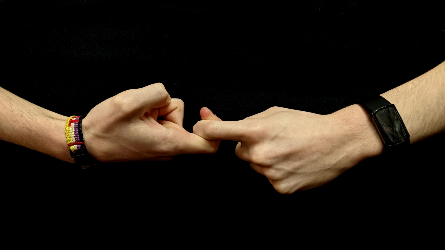 Two hands forming part of a sign-language gesture against a dark background; representative image