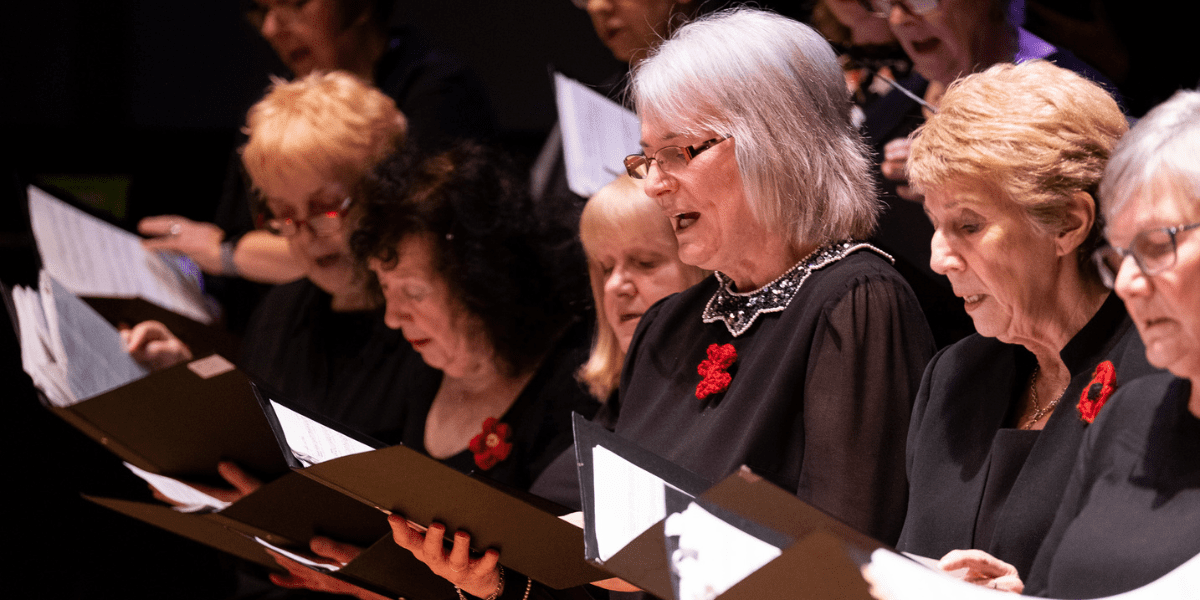 Members of Middlesbrough Town Hall Community Choir singing from choir folders during a performance