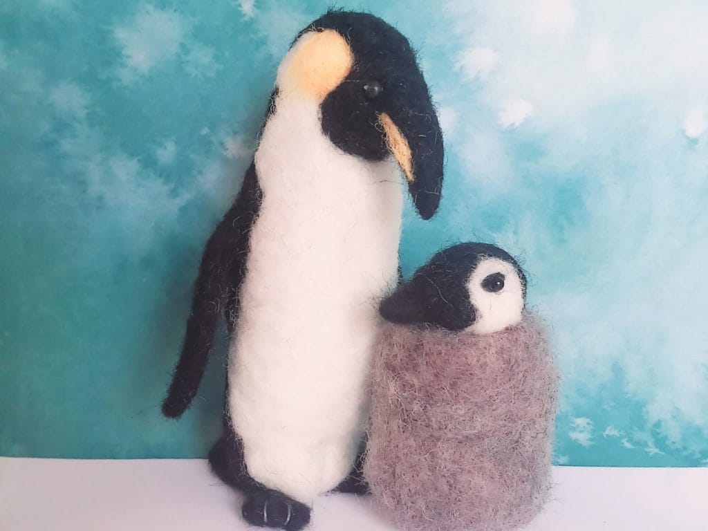 Two handmade needle-felted penguins against a blue background, promoting the ARC Stockton workshop.