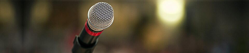 A microphone on a stand, used as an illustrative comedy image.