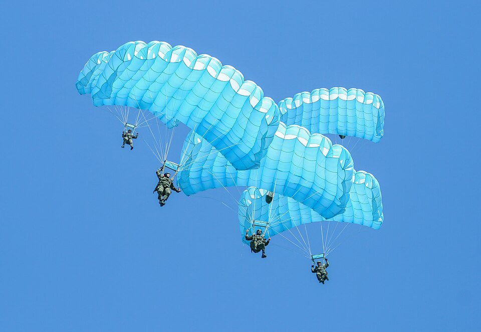 Parachutists under blue canopies; illustrative photograph, not the MFC Foundation fundraiser.