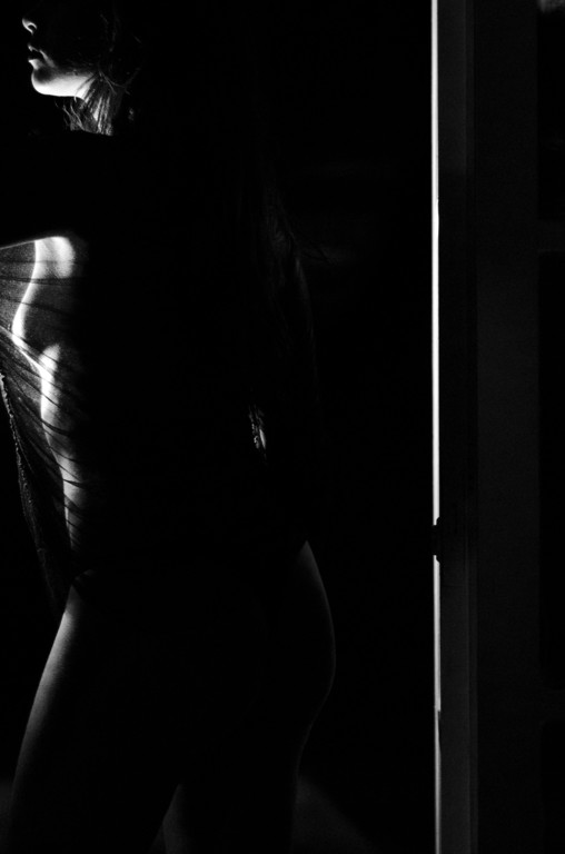 Ensaio sensual em preto e branco, silhueta em contraluz junto à porta