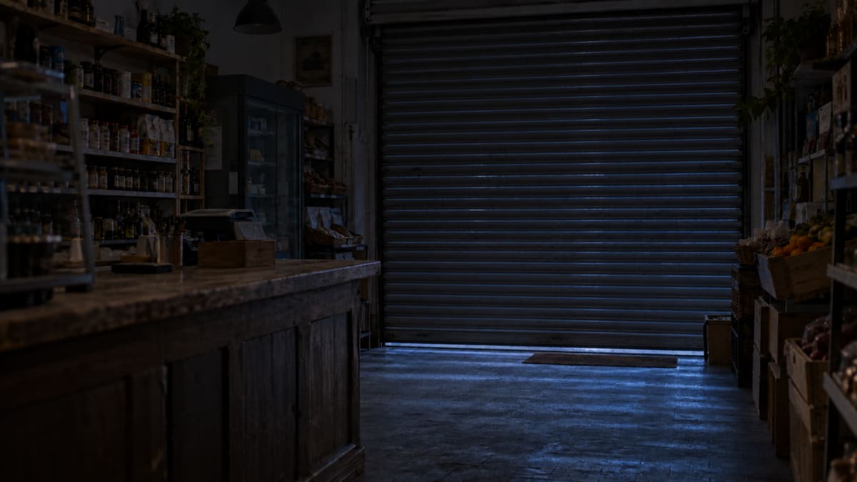 The same shop at night, lights off and shutter down