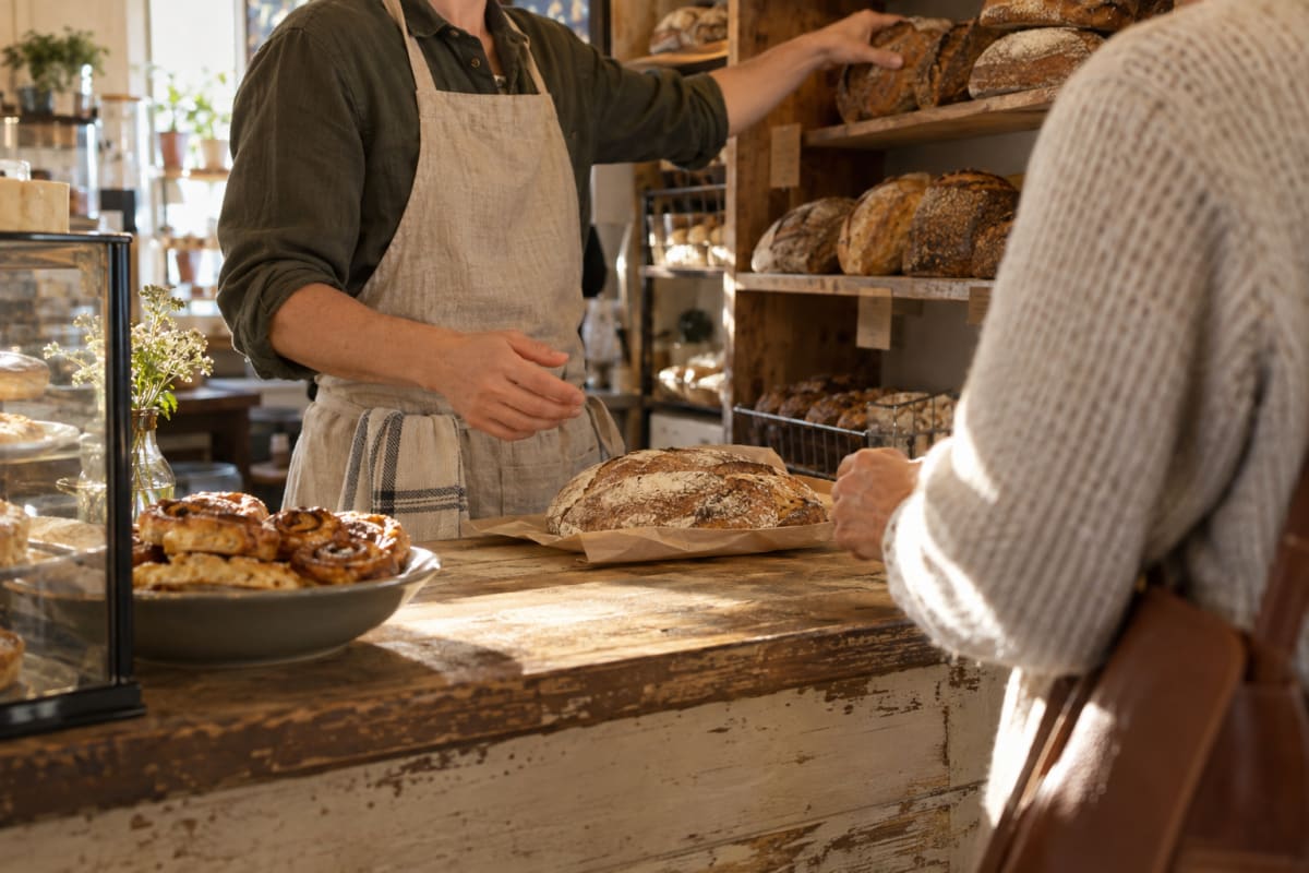 A baker reaching for the usual loaf as a regular waits