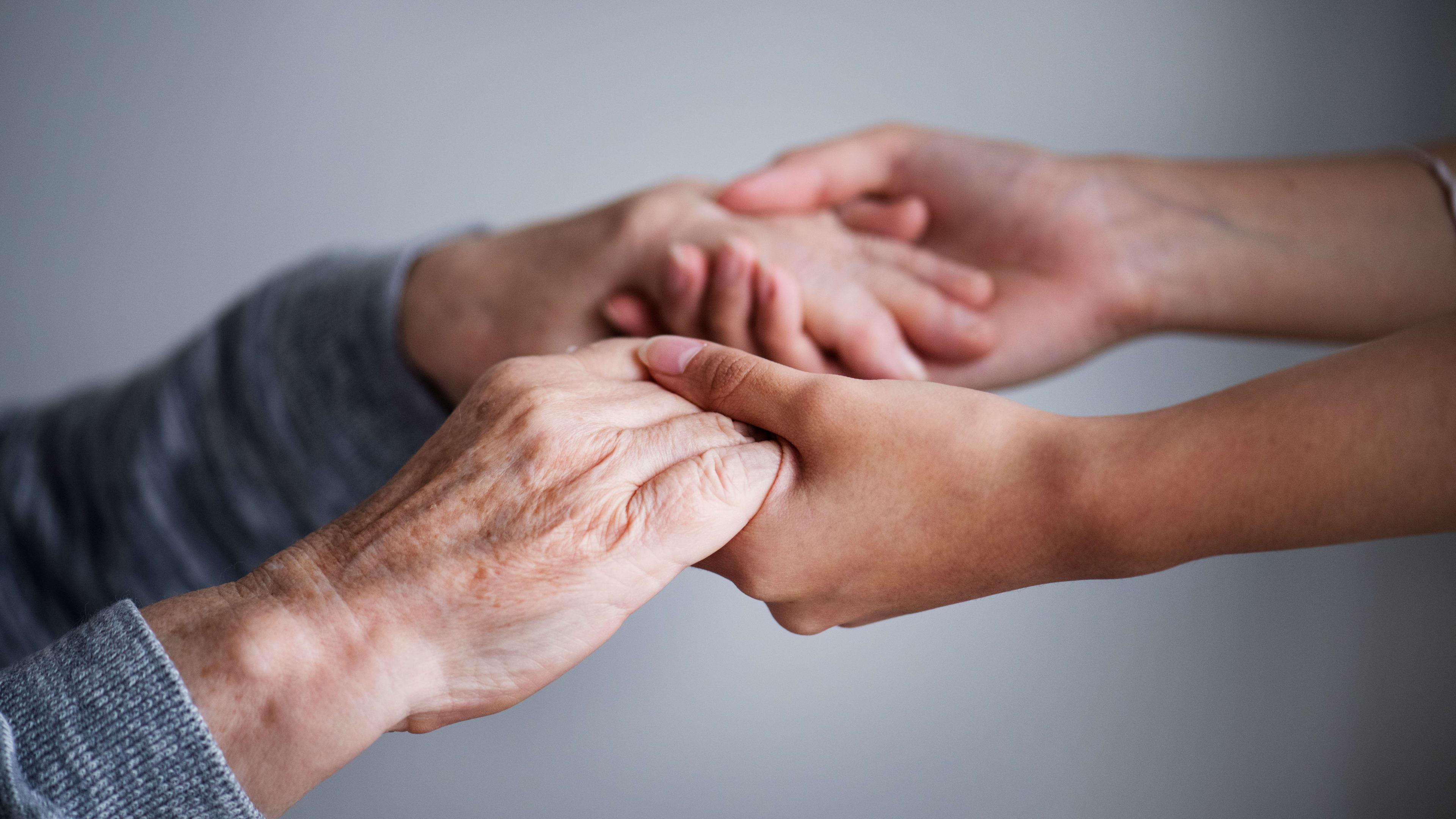 Hände einer jungen und älteren Person, die sich gegenseitig unterstützen