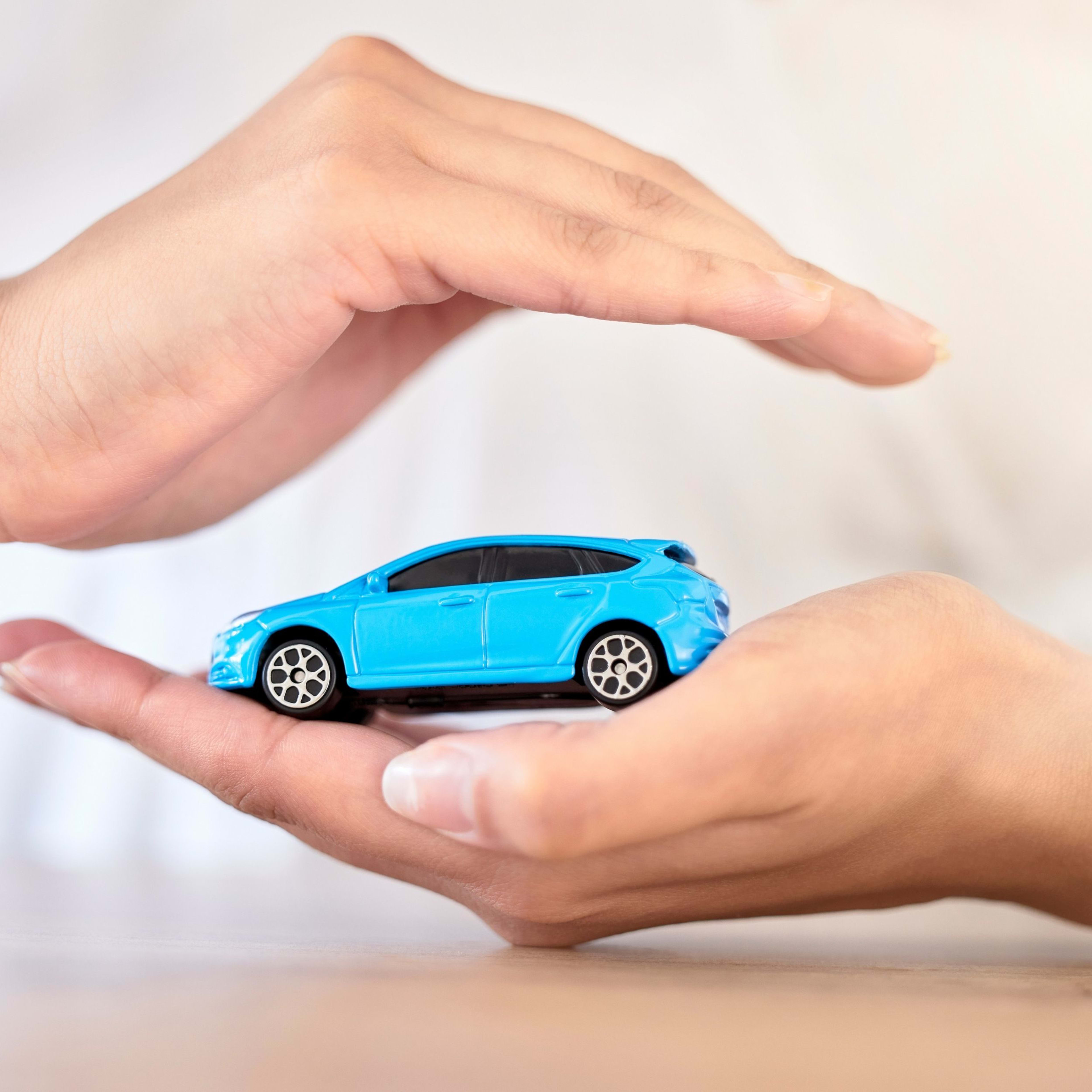 Blaues Auto, das von offener Handfläche beschützt wird 