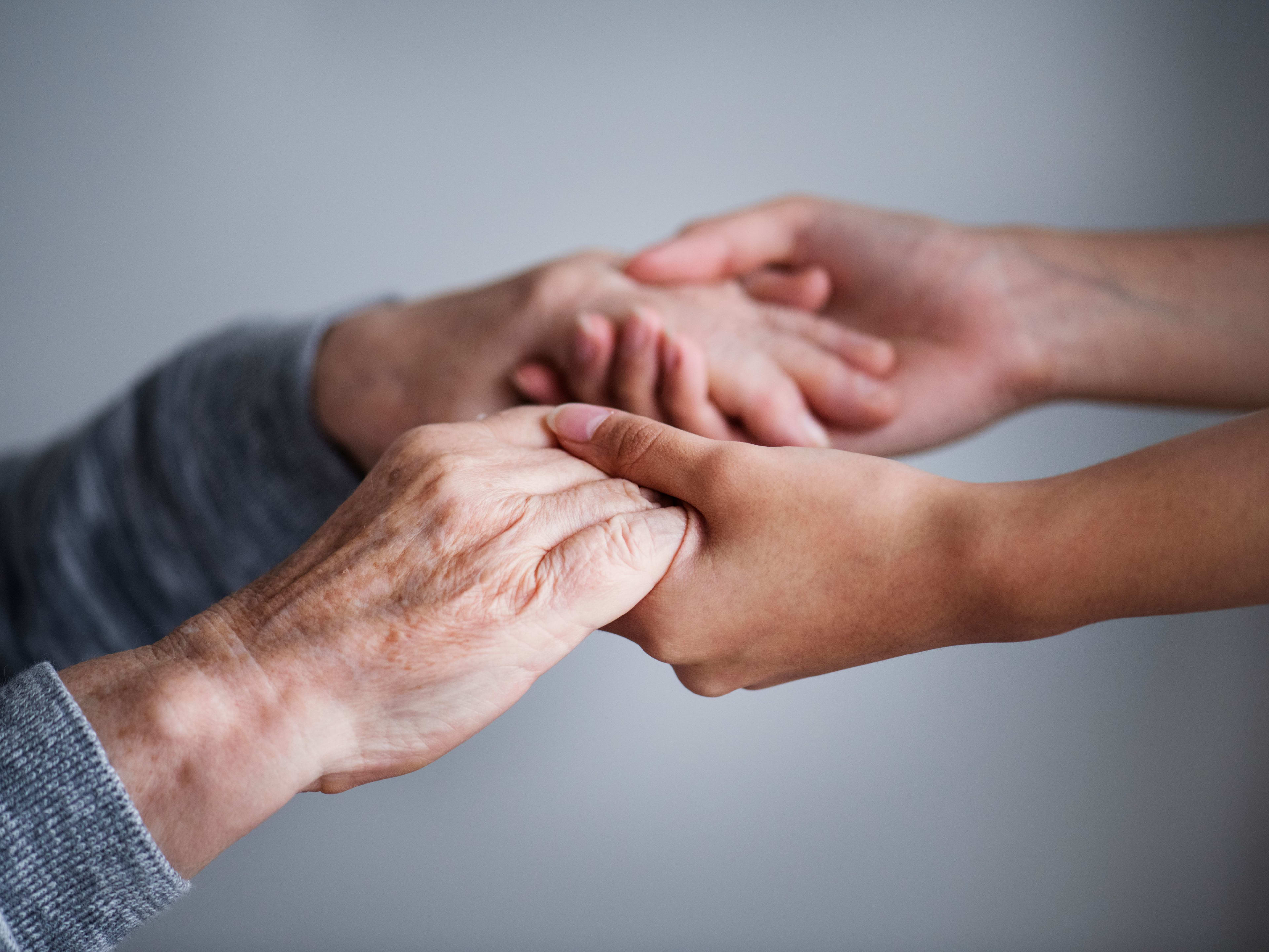 Hände einer jungen und älteren Person, die sich gegenseitig unterstützen