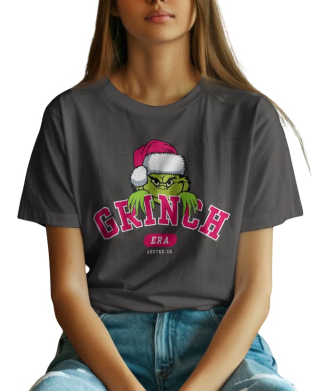 Camiseta gris con estampado del Grinch usando gorro navideño y texto en rosa