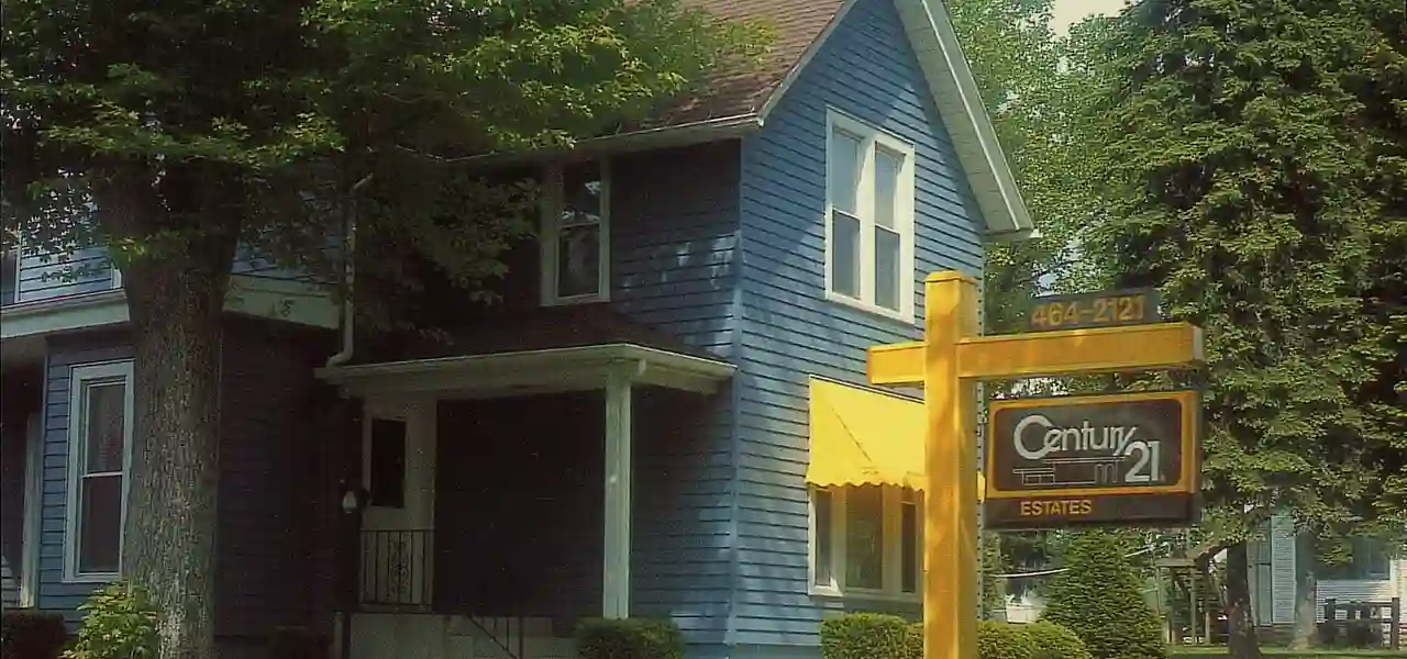 Century 21 real estate office with yellow signage in front of blue house, Valparaiso, Indiana, 1985.