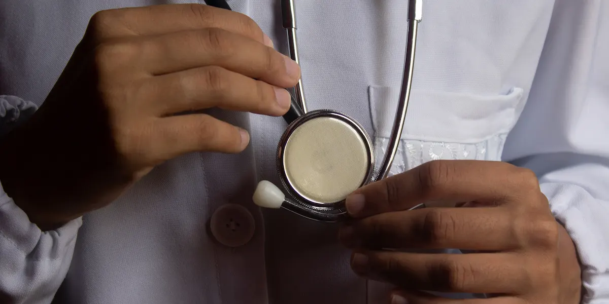 Close-up of a doctor in a white coat holding a stethoscope in a clinical setting, 2025