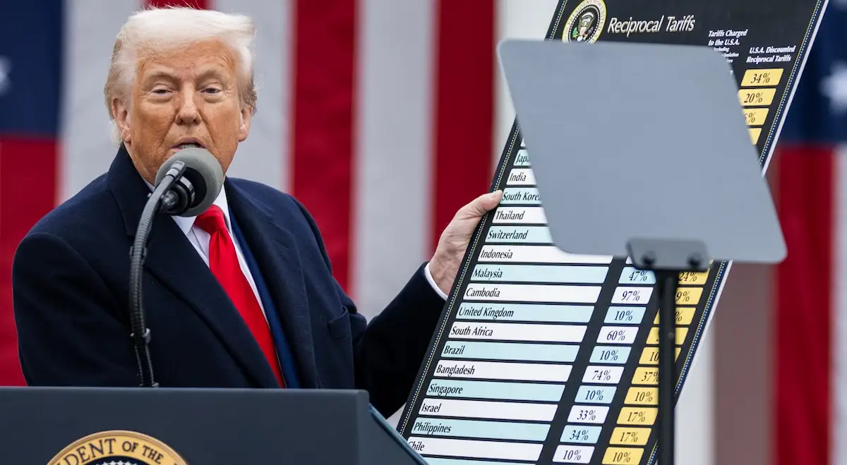 Former President Donald Trump standing beside a chart outlining his new tariff measures on April 2, 2025
