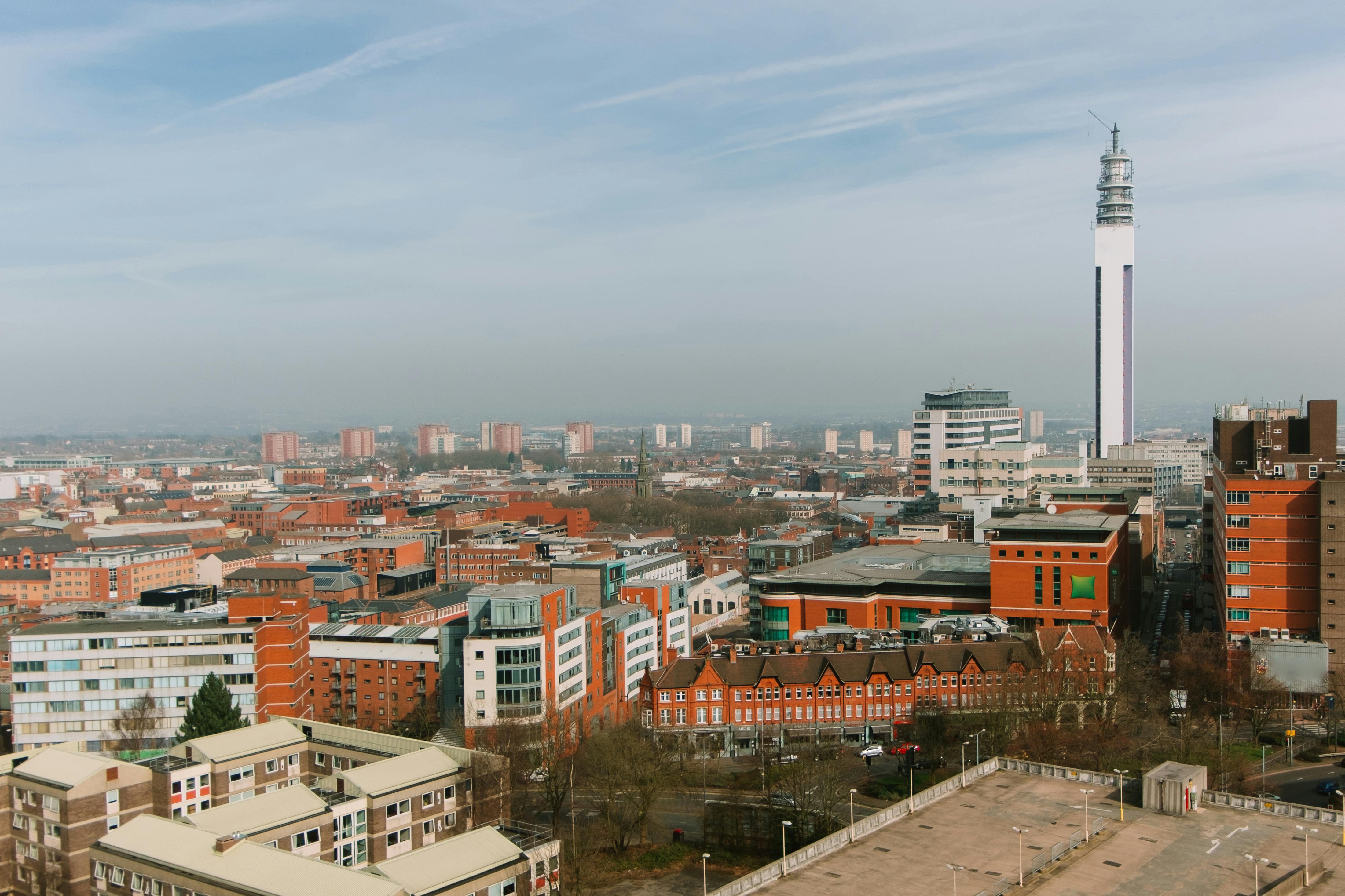 Birmingham City guide: Image shows a panoramic view of Birmingham city centre featuring a mix of modern and historic buildings, with the prominent white BT Tower rising above the skyline under a lightly clouded blue sky.