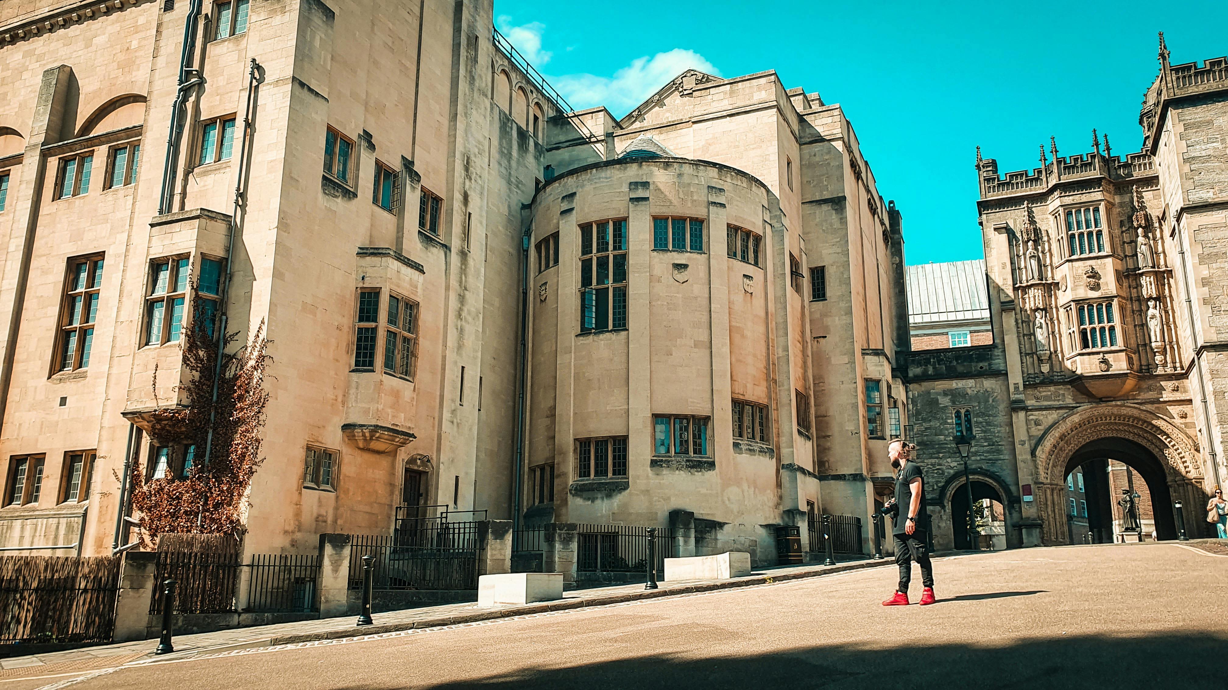 A student stands in front of the historic Wills Memorial Building at the University of Bristol on a sunny day, highlighting one of the city&rsquo;s key landmarks for students relocating for university.
