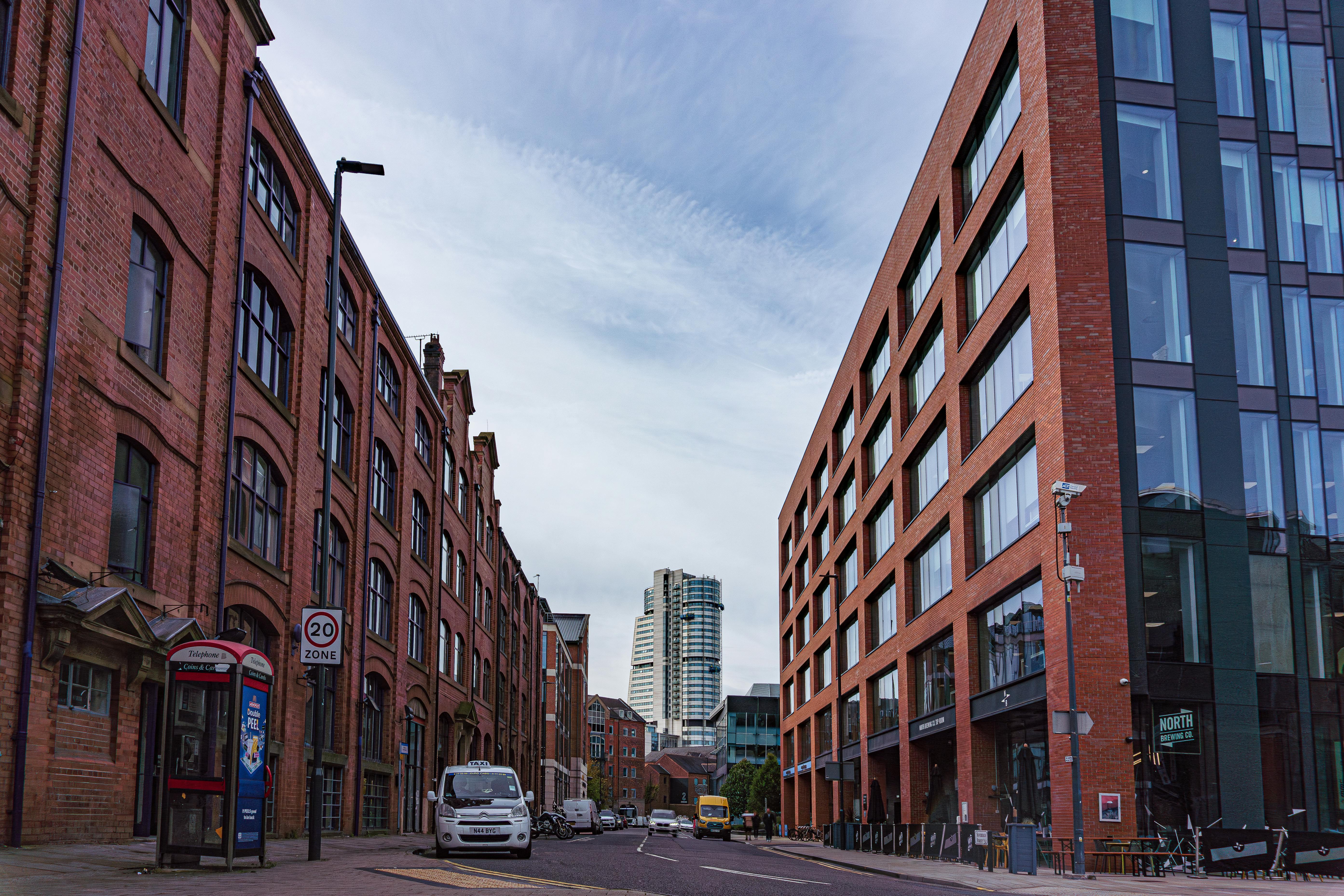 Moving to Leeds: Street view in central Leeds showing a mix of historic red-brick warehouses and modern office buildings, with the city’s skyline and Bridgewater Place visible in the distance.