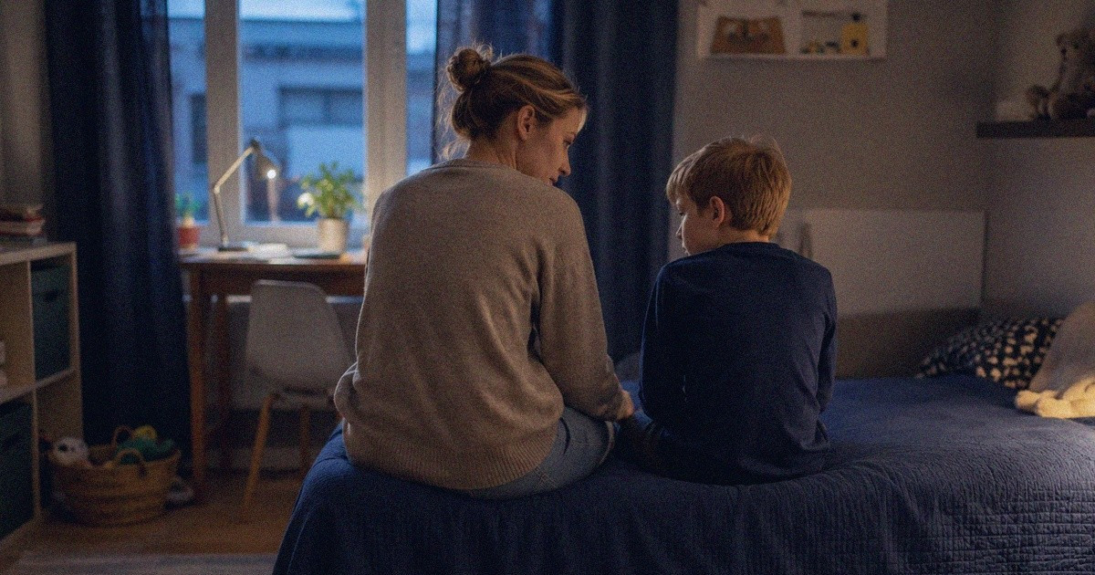 Vanhempi istumassa rauhallisesti lapsen vierellä tunnekuohun jälkeen.