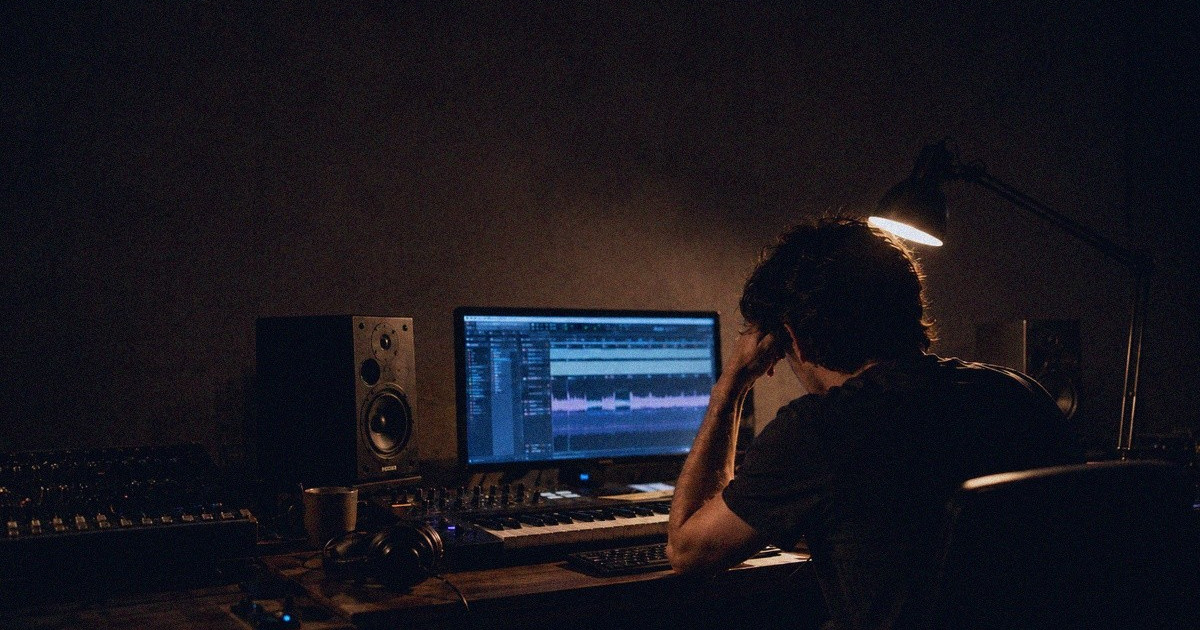 Muusikko katsoo studiossa näyttöjä, joille tulvii valtava määrä geneerisiä digitaalisia musiikkijulkaisuja.