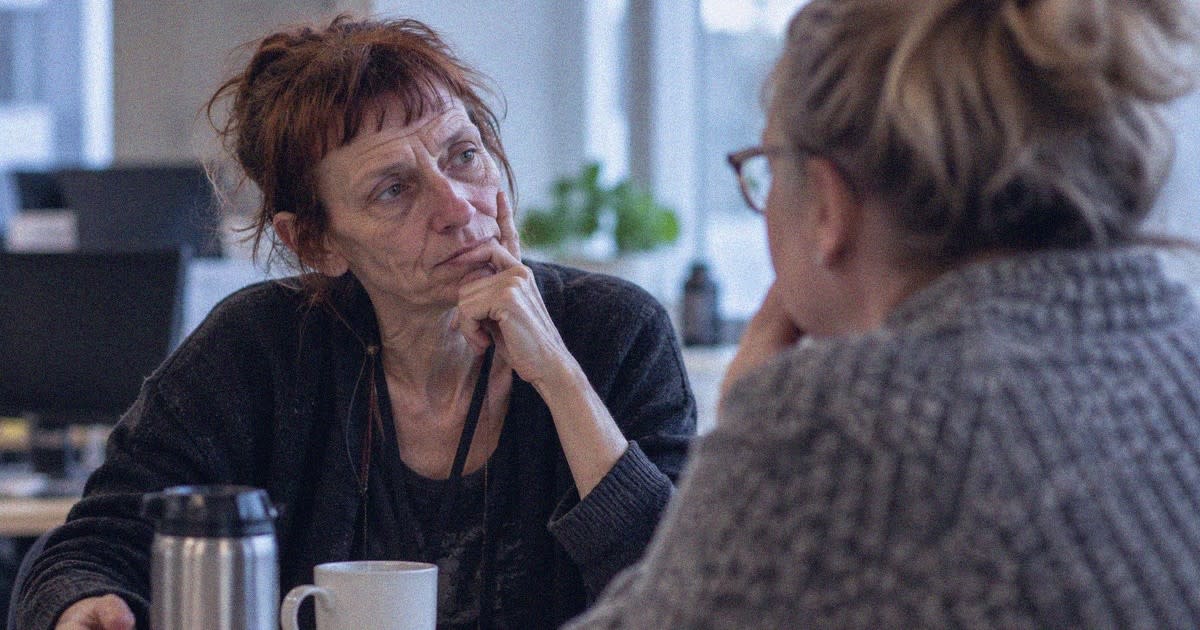 Nainen pohtii asiaa keskustellessaan työkaverin kanssa.