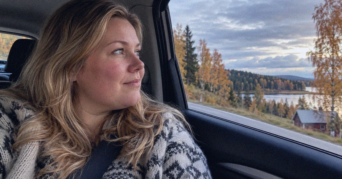Matkustaja katselee syksyistä maisemaa auton ikkunasta maantiellä.