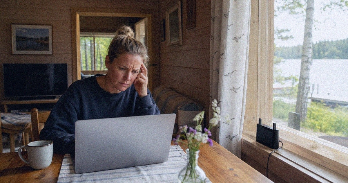 Etätyötä tekevä mökkeilijä käyttää kannettavaa tietokonetta ikkunan viereen sijoitetun mobiilireitittimen avulla