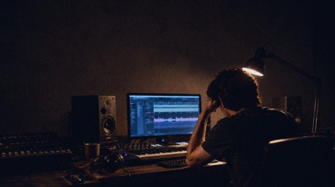 Muusikko katsoo studiossa näyttöjä, joille tulvii valtava määrä geneerisiä digitaalisia musiikkijulkaisuja.