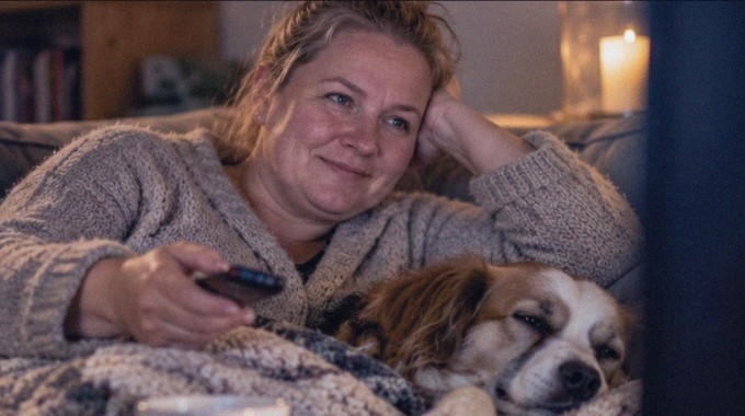 Nainen katsoo tuttua televisiosarjaa kotisohvalla.