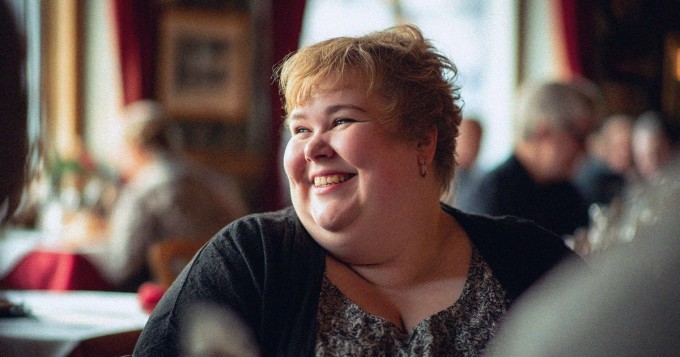 Nainen nauraa ravintolassa.