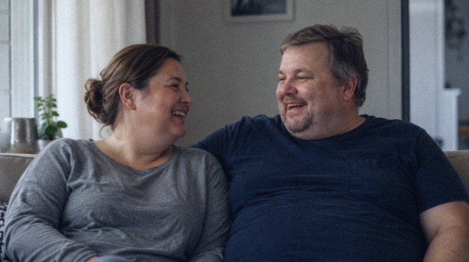 Pariskunta nauraa yhdessä rennosti kotisohvalla