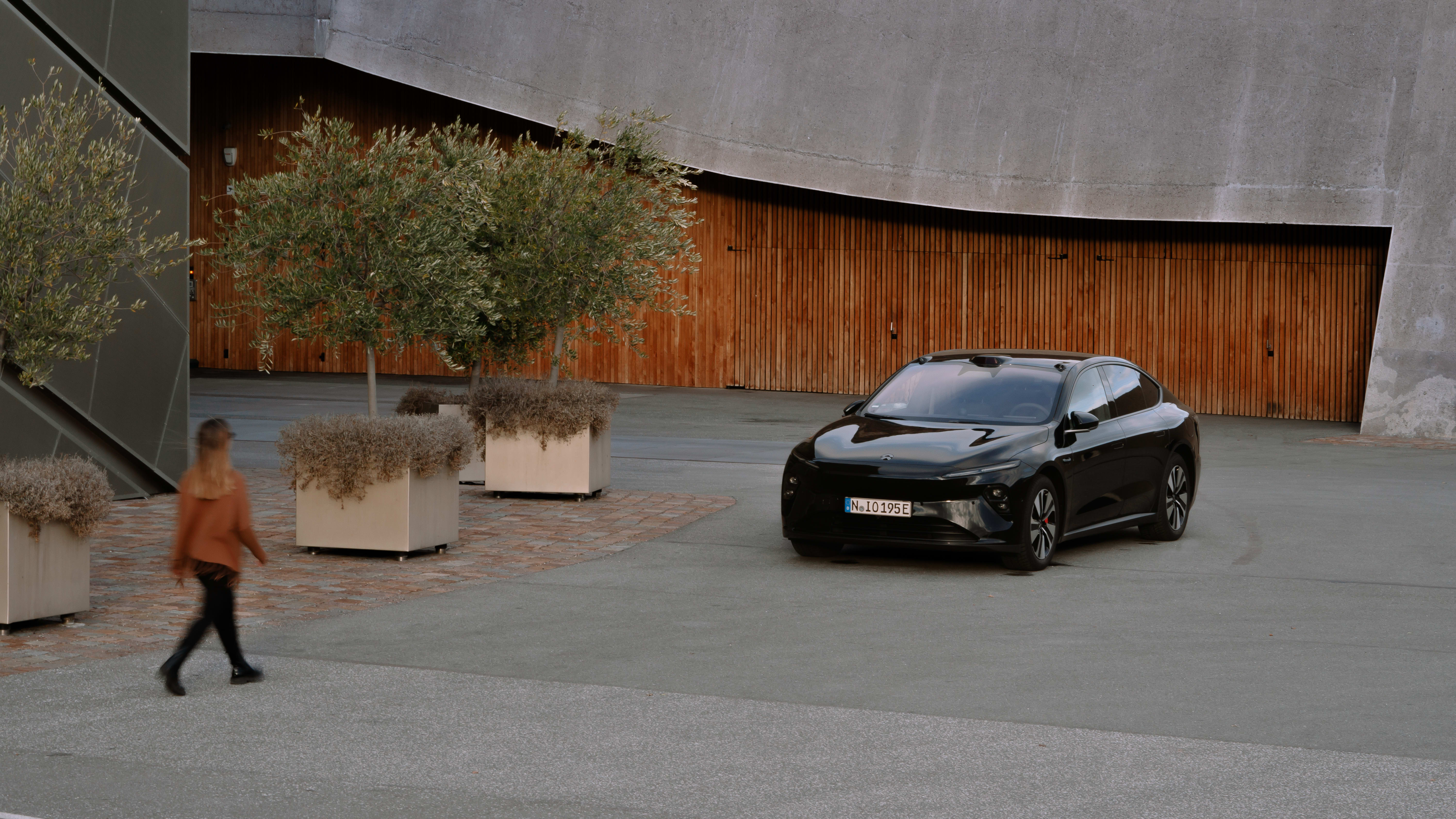 Eine Frau läuft auf einen Nio von FINN zu.