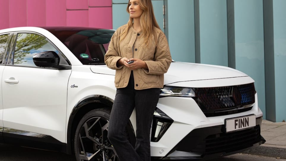 Eine Frau steht vor einem Renault Rafale von FINN.