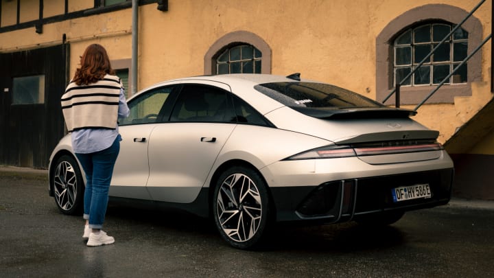 Eine Frau steht neben einem Hyundai IONIQ 6 von 