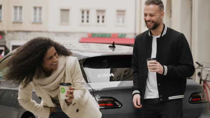 Ein Paar steht vor einem FINN Auto. 