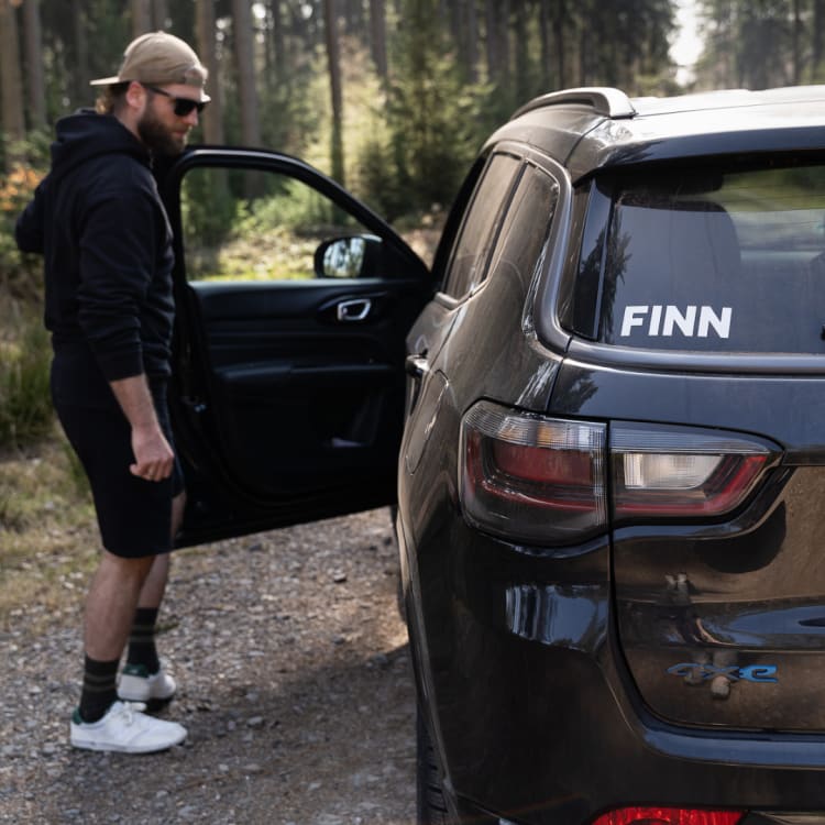 Ein Mann öffnet die Fahrertür eines FINN Autos.